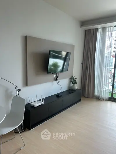 Modern living room with mounted TV and sleek furniture, featuring large window with city view.