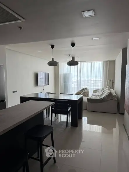 Modern living room with sleek furniture and large windows offering natural light and city views.