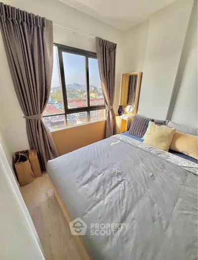 Cozy bedroom with large window offering scenic city views, featuring elegant curtains and modern decor.