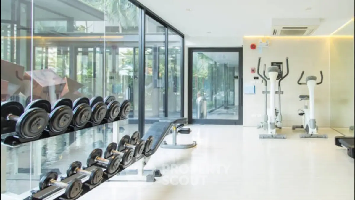 Modern gym with glass walls and fitness equipment in luxury building.