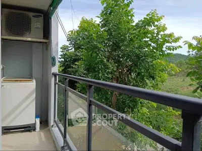 Charming balcony with lush green view and convenient laundry setup.