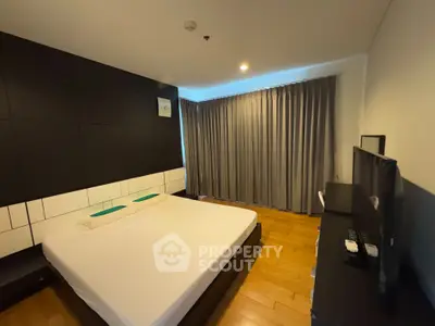 Spacious modern bedroom with wooden flooring and large window curtains