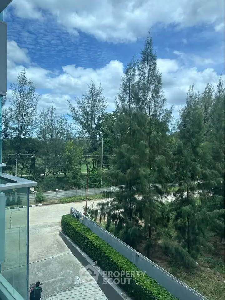 Serene view from a modern building with lush greenery and clear blue sky.