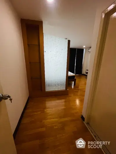 Cozy bedroom with wooden flooring and modern glass partition in a stylish apartment.