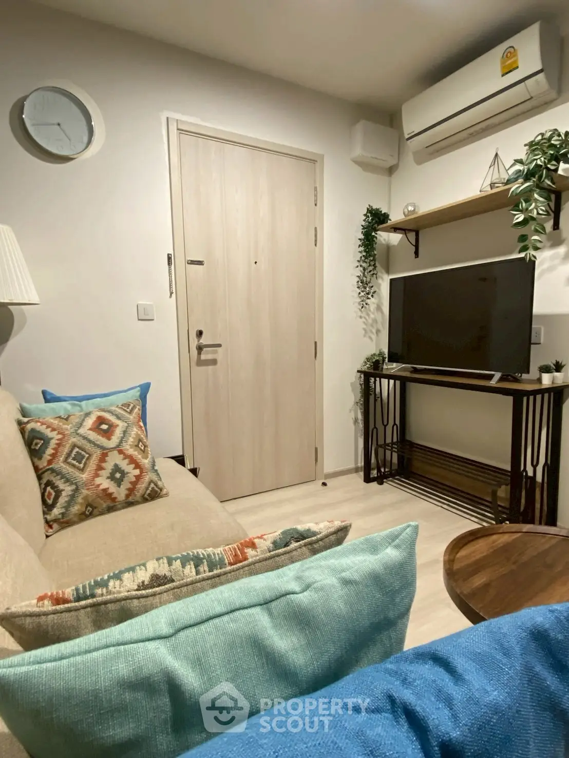 Cozy living room with modern decor, featuring a comfortable sofa, wall-mounted TV, and stylish shelving.