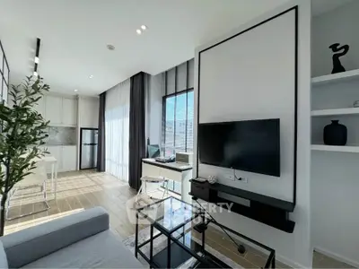 Modern living room with sleek decor and natural light, featuring a stylish kitchen and work area.