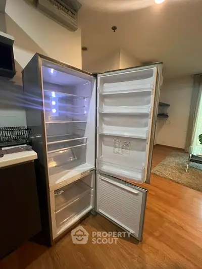 Modern kitchen with open stainless steel refrigerator and wooden flooring