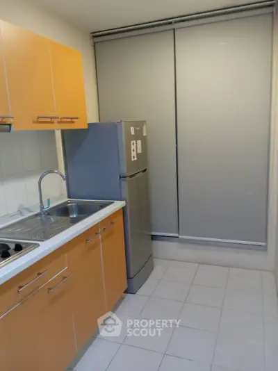 Modern kitchen with sleek cabinets and stainless steel fridge in a compact layout.