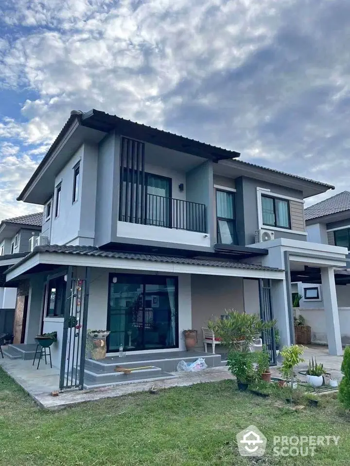 Modern two-story house with landscaped garden and stylish facade under a cloudy sky.