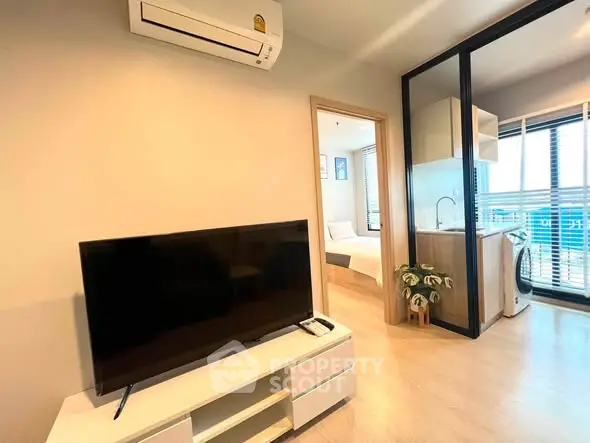 Modern apartment interior with TV, air conditioning, and open kitchen layout.