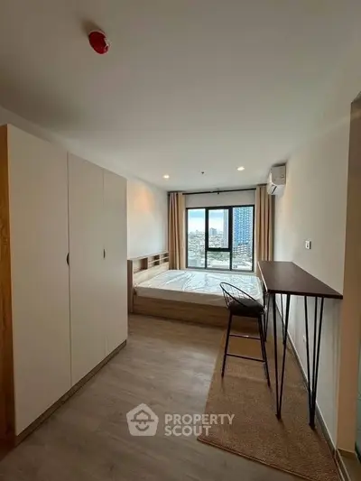 Modern bedroom with city view, featuring minimalist furniture and large window.
