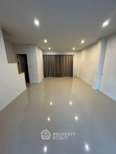 Spacious empty living room with glossy tiled floor and modern lighting
