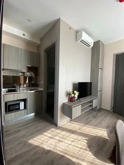 Modern compact living room with integrated kitchen, featuring sleek cabinetry and natural light.