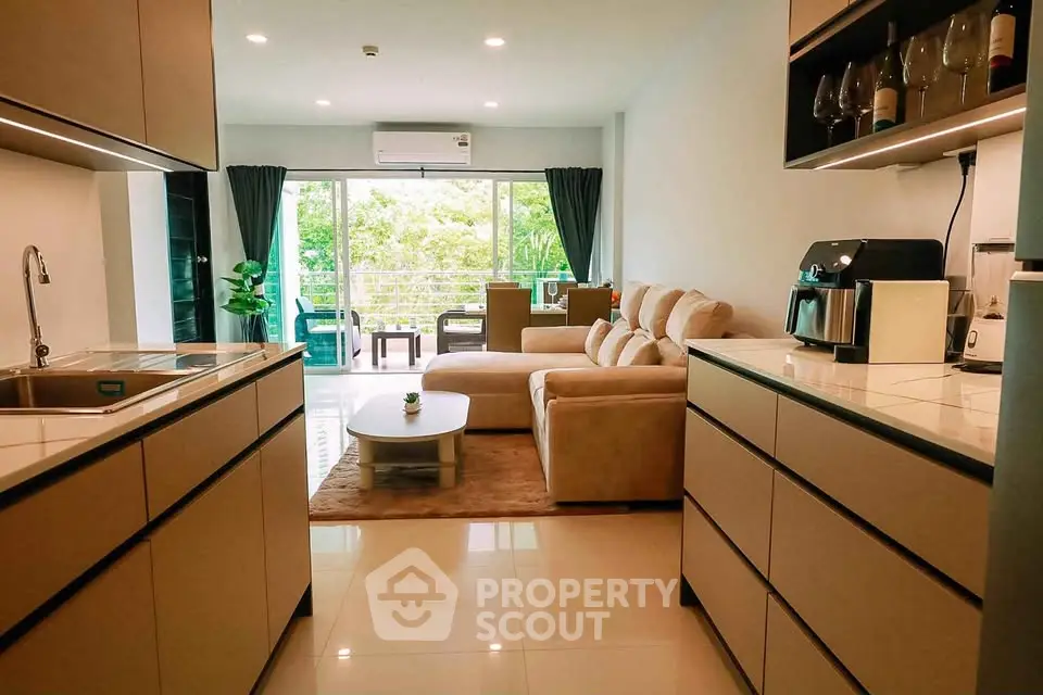 Modern open-layout kitchen and living room with cozy seating and lush garden view.