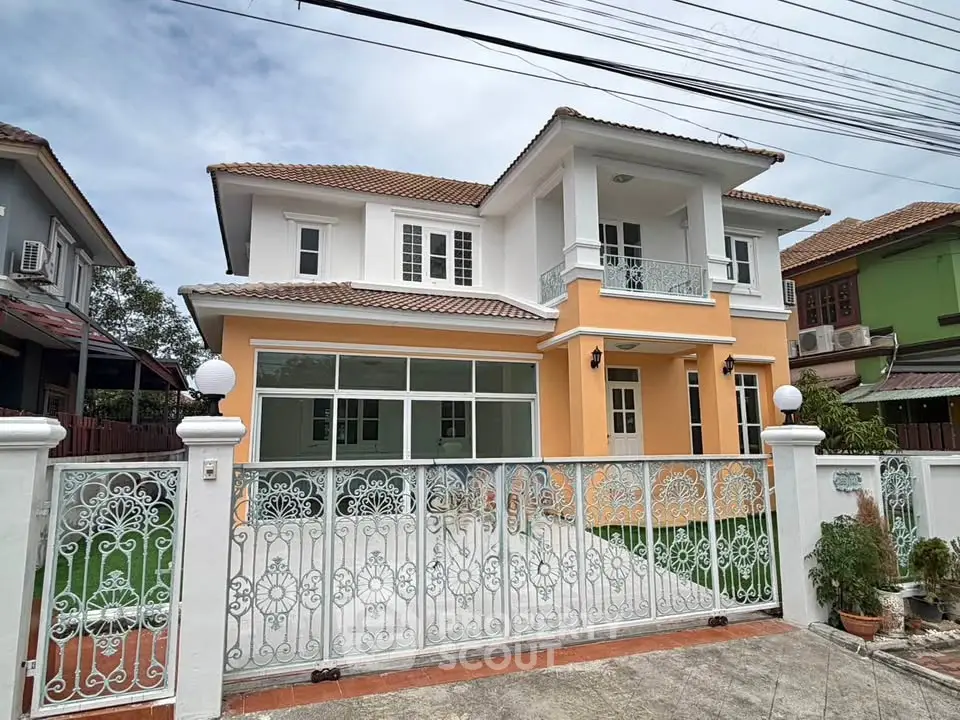 Charming two-story house with elegant wrought iron gate and spacious front yard.