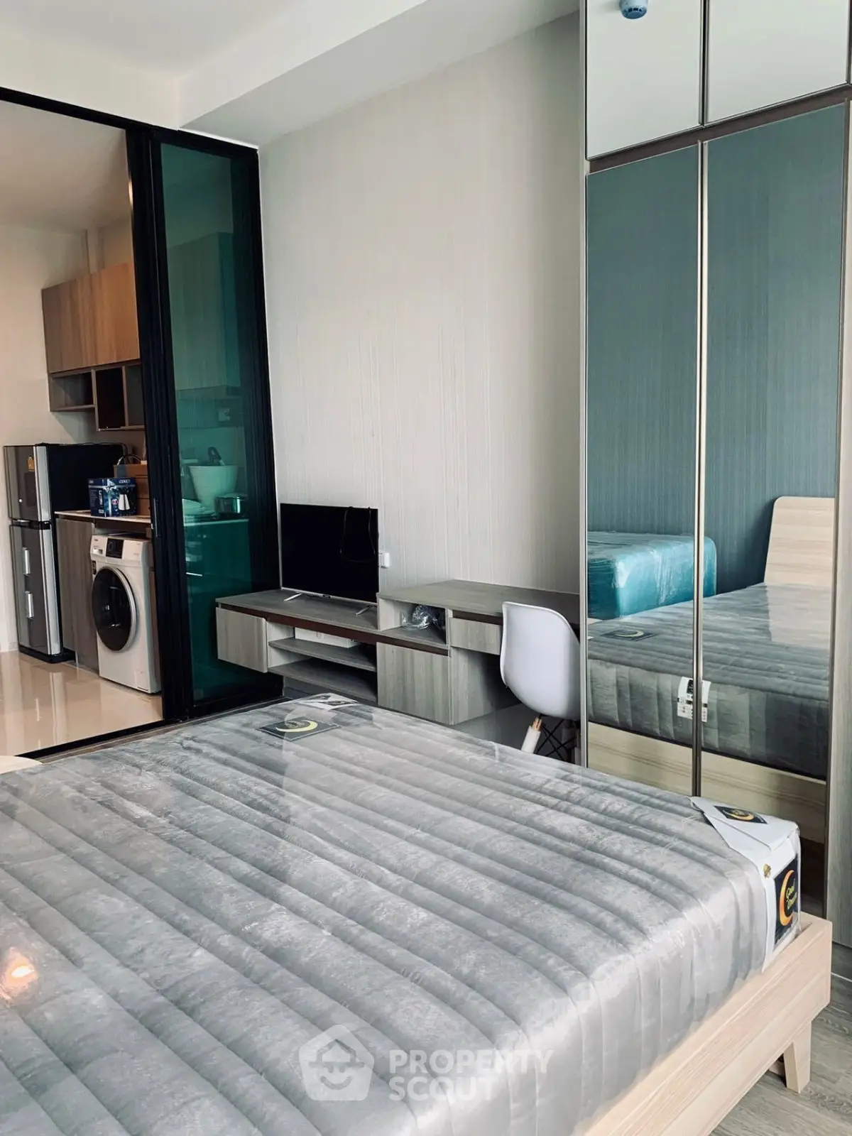 Modern bedroom with mirrored wardrobe and compact workspace in stylish apartment.