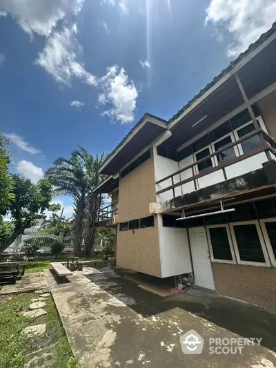 Charming two-story house with spacious garden and patio under clear blue sky.