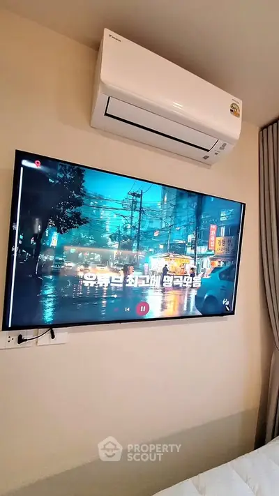 Modern living room with wall-mounted TV and air conditioning unit, showcasing a cozy and comfortable ambiance.