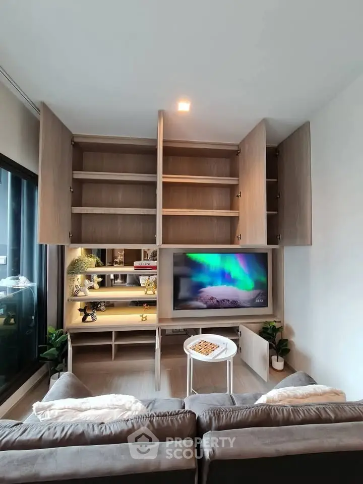 Modern living room with built-in wooden cabinets and TV, cozy sofa, and stylish decor.