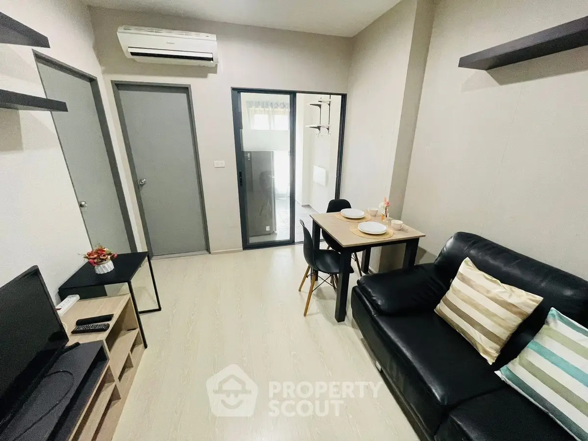Modern living room with sleek black sofa and dining area in stylish apartment.