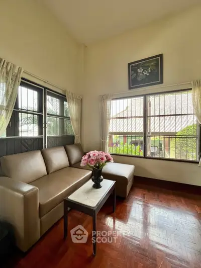 Charming living room with cozy sofa and large windows offering natural light and garden view.