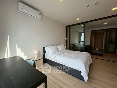 Modern bedroom with sleek design, featuring a comfortable bed, wooden flooring, and ample natural light.