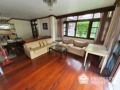 Spacious living room with wooden floors and large windows overlooking garden