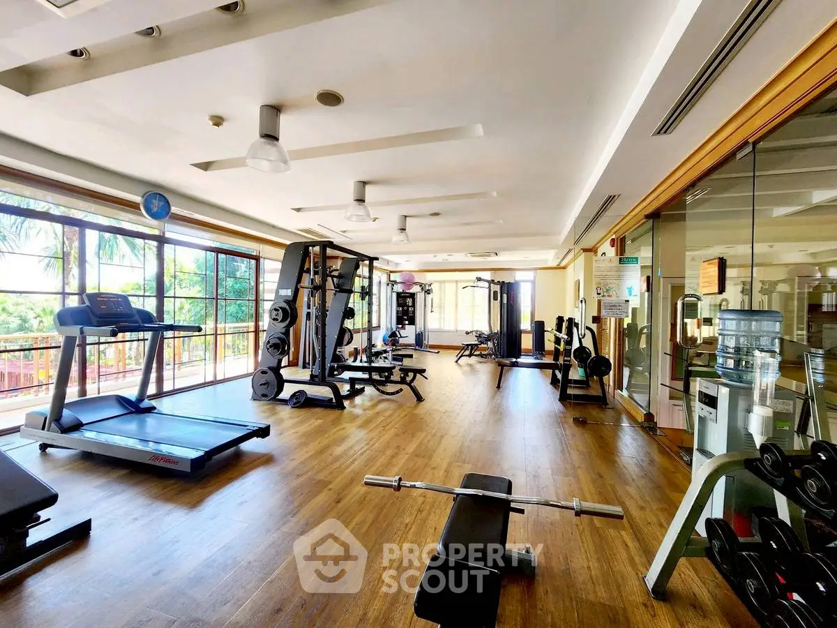 Spacious gym with modern equipment and large windows offering scenic views.