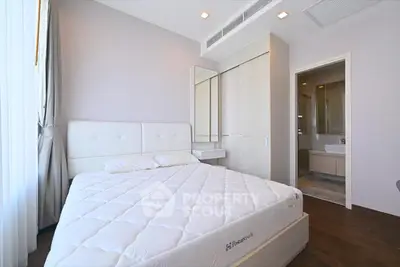 Modern bedroom with sleek design and ensuite bathroom, featuring a comfortable bed and ample natural light.
