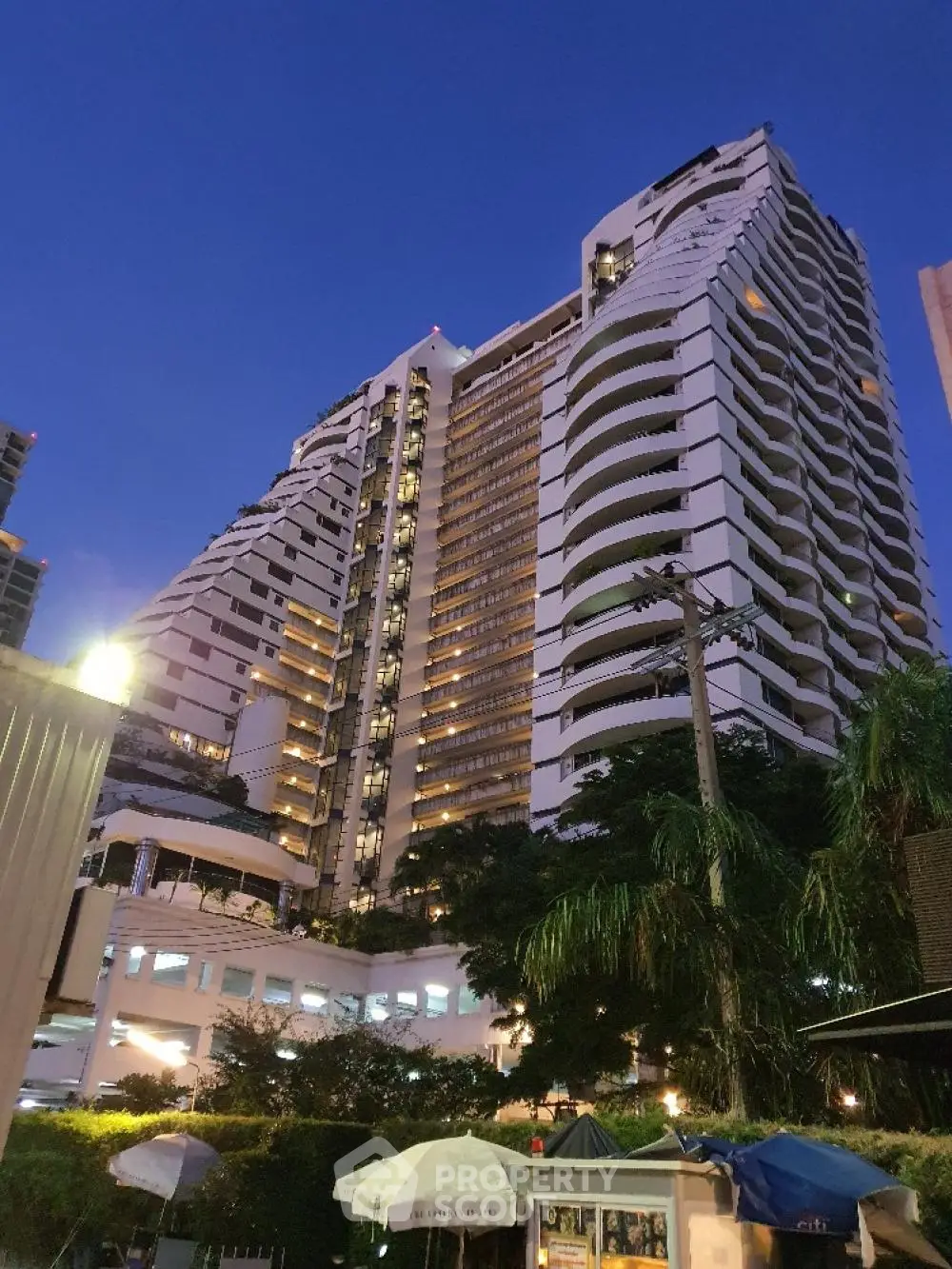 Stunning high-rise building with modern architecture and lush surroundings at dusk.