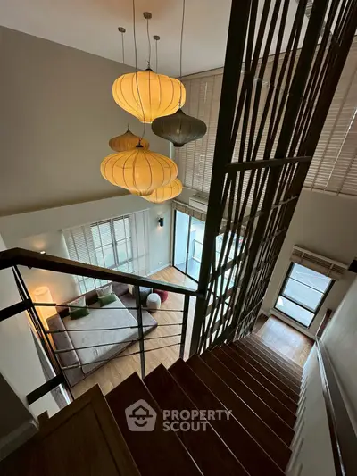 Stunning modern duplex with elegant staircase and stylish lighting, offering a spacious and bright living area.