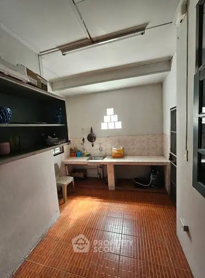 Spacious kitchen with open layout and natural light, featuring tiled flooring and ample counter space.