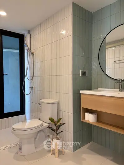 Modern bathroom with sleek design, featuring a round mirror, shower, and stylish tiles.