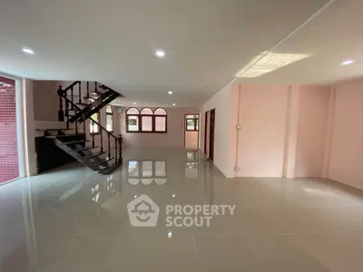Spacious open-plan living area with modern staircase and glossy tile flooring