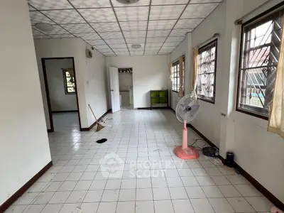 Spacious living room with tiled floor and large windows, ideal for natural light and ventilation.