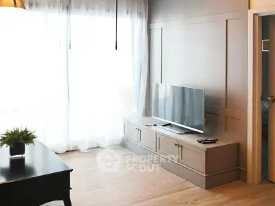 Modern living room with natural light, sleek TV setup, and elegant wooden flooring.