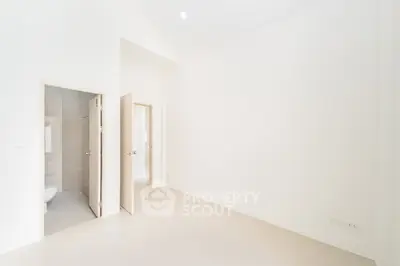 Spacious empty room with open door leading to modern bathroom, ideal for customization.