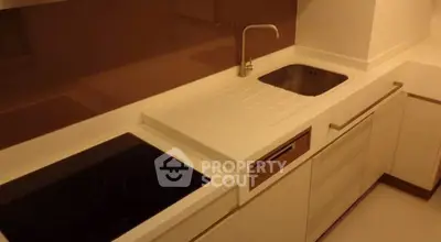 Modern kitchen with sleek white cabinetry and built-in electric cooktop.