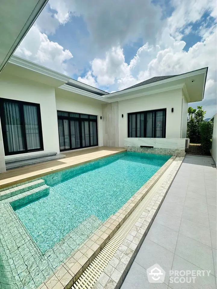 Luxurious modern villa with private swimming pool and elegant patio under a clear blue sky.