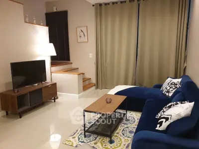 Modern living room with blue sofa, TV, and stylish decor