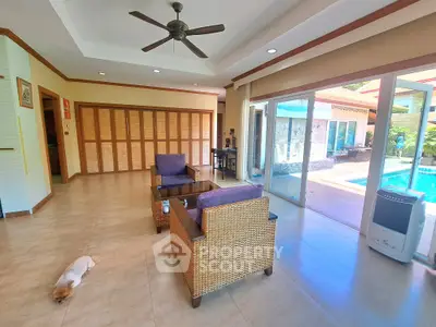 Spacious living room with pool view and elegant wicker furniture in a modern home.