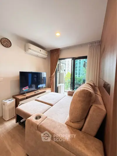 Cozy living room with modern sofa, large TV, and balcony view in stylish apartment.