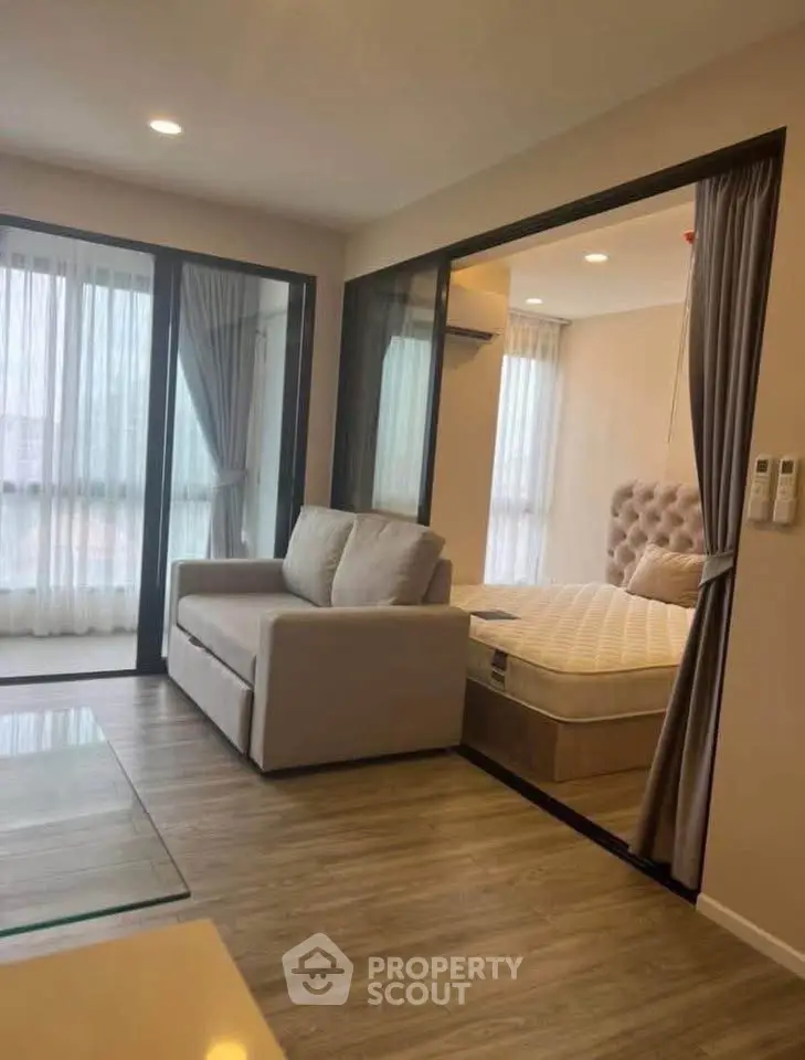 Modern apartment with cozy living room and adjacent bedroom, featuring large windows and elegant decor.