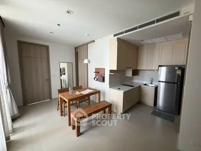 Modern kitchen with wooden dining set and stainless steel fridge in cozy apartment.