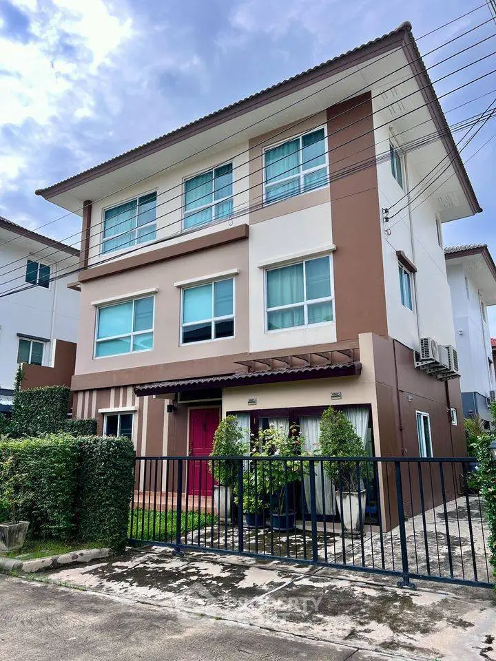 Modern three-story townhouse with stylish facade and gated entrance in a suburban neighborhood.