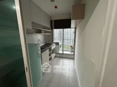 Modern compact kitchen with city view, sleek cabinetry, and tiled flooring in urban apartment.
