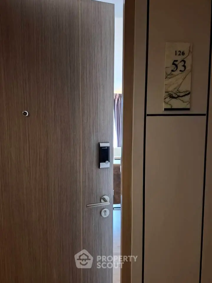 Modern apartment entrance with sleek wooden door and digital lock system.