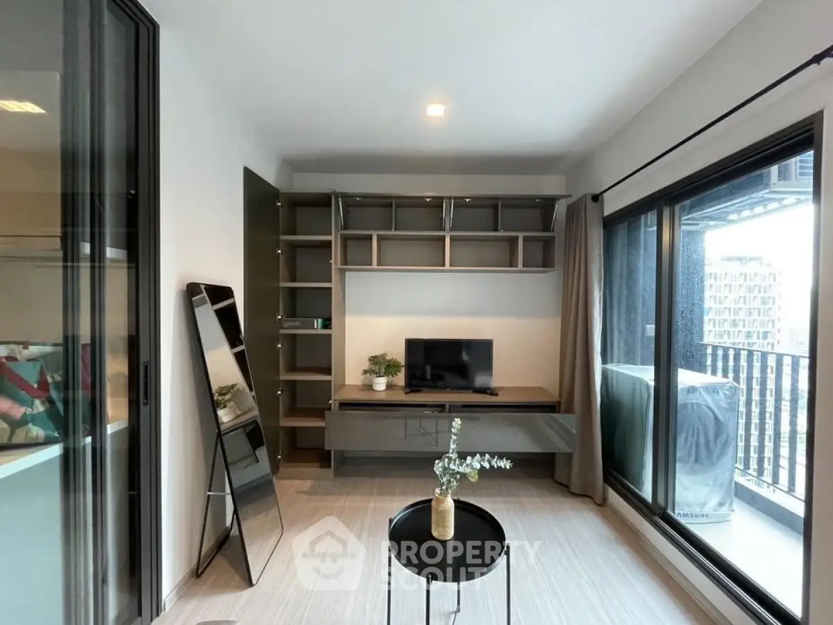Modern living room with balcony view, sleek furniture, and natural light in urban apartment.