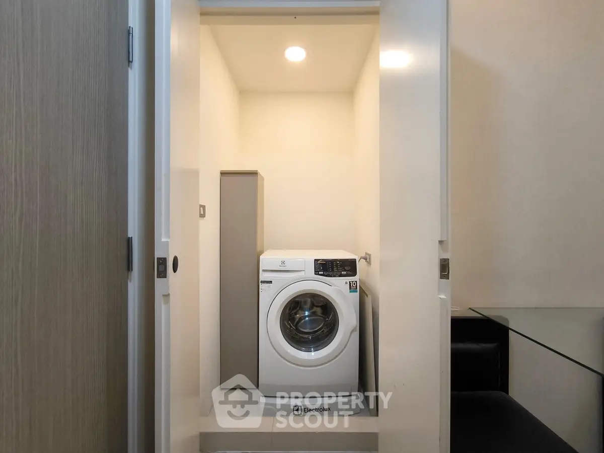 Compact laundry area with modern washing machine in a sleek storage space.
