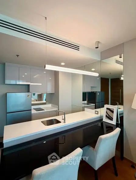 Modern kitchen with sleek design, featuring a breakfast bar and stainless steel appliances.